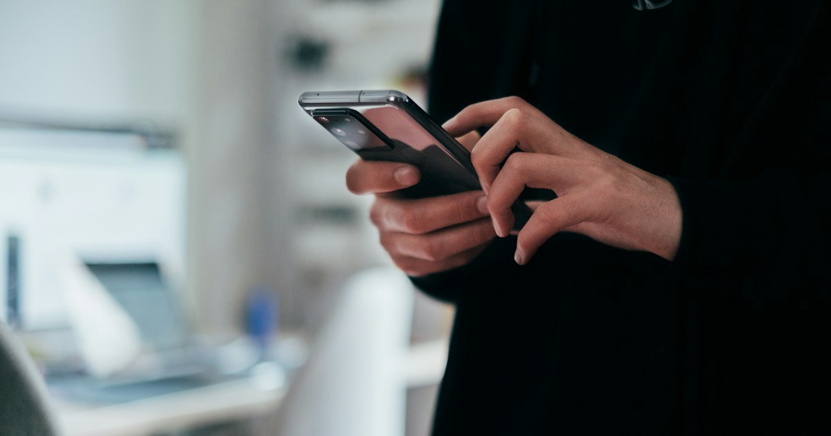 Persona usando telefono movil para representar correo corporativo seguro, MFA y prevencion de phishing