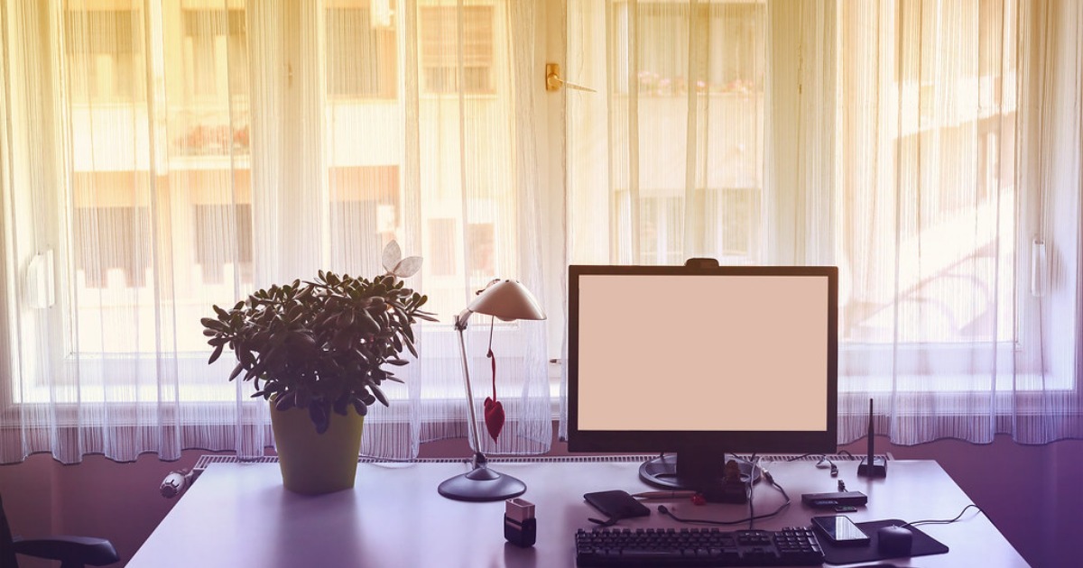 Puesto de trabajo con computadora de escritorio e iluminación natural Computadora de escritorio junto a una ventana iluminada, imagen ilustrativa de un puesto de trabajo