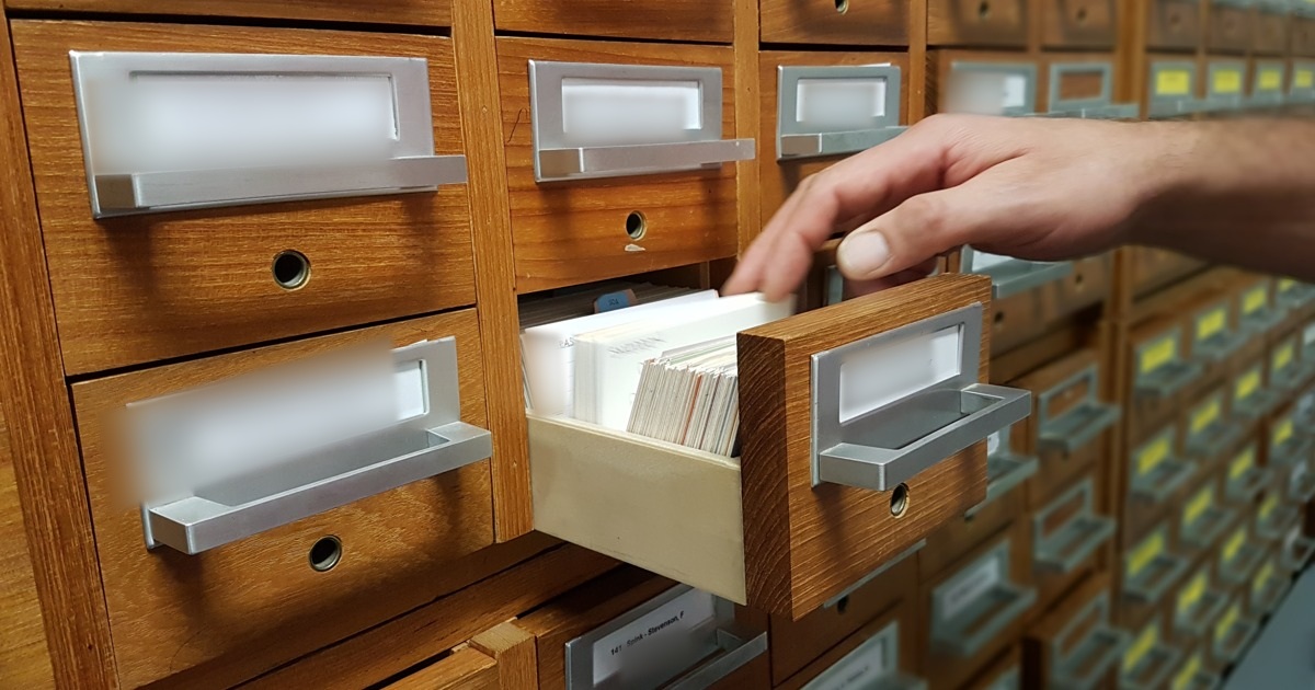 Mano seleccionando una ficha en un archivo de madera, fotografía ilustrativa de selección documental