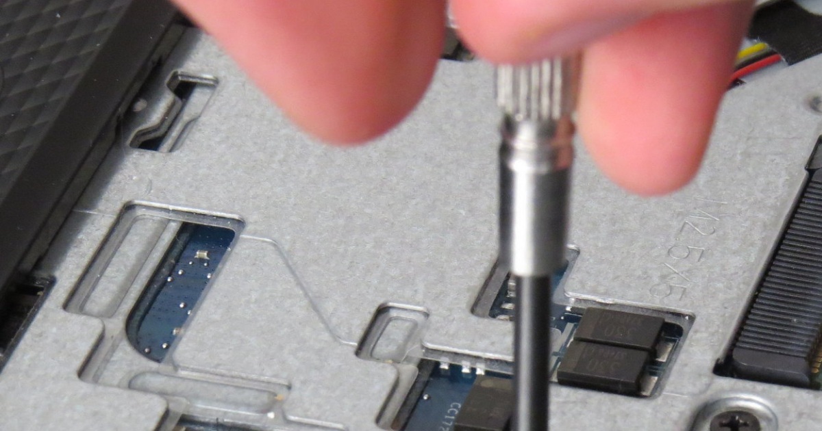 Manos con destornillador durante el mantenimiento de una computadora Detalle de una mano usando un destornillador durante mantenimiento físico de una computadora
